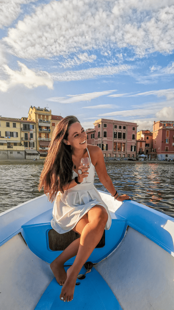 ragazza che sorride in barca con un bicchiere di prosecco in mano