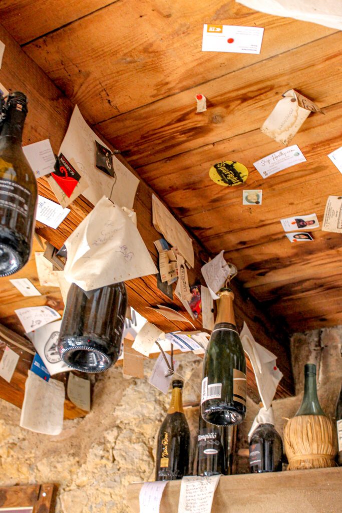 Osteria senz'oste: soffitta di legno, bottiglie e fogli appesi
