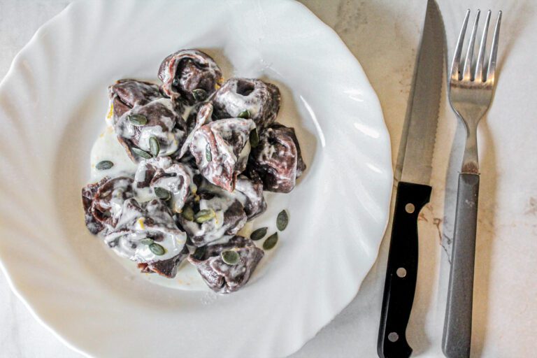 tortelli di zucca: piatto bianco, posate, pasta fresca al cacao