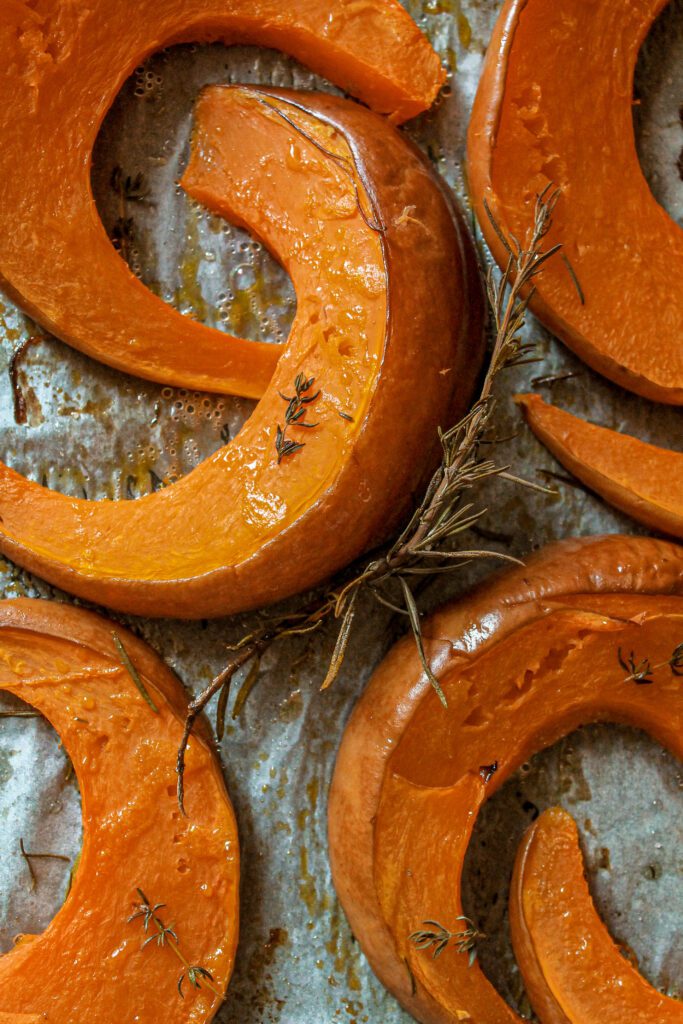 zucca al forno: arancione, teglia, fette di zucca al forno, rametto di rosmarino