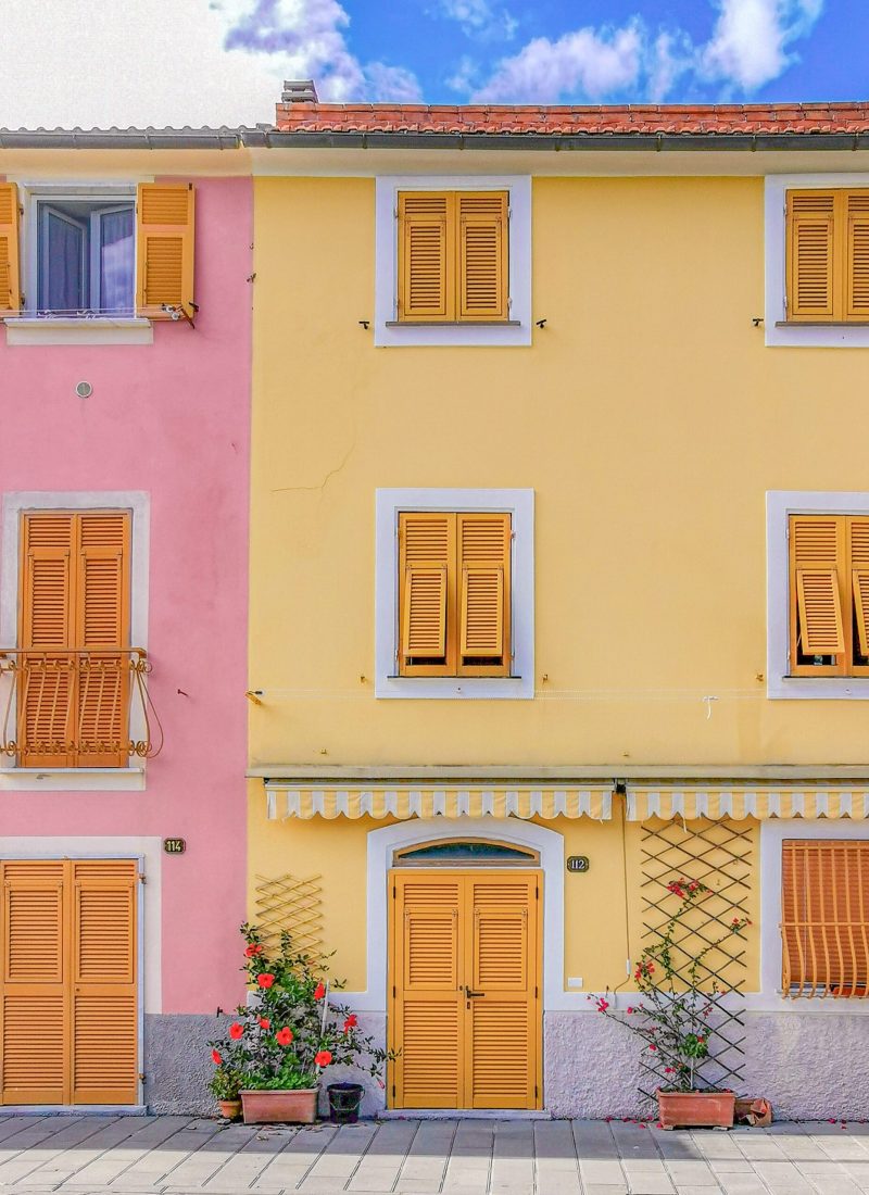 facciata casa rosa e gialla, persiane arancioni